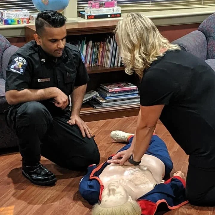 Instructor guiding hands-on CPR practice on a training manikin